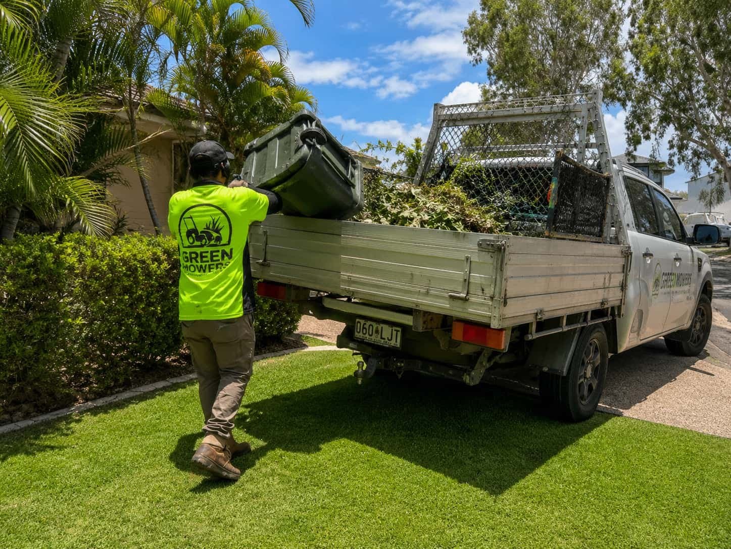 Green Mowers team member loading green waste into a work vehicle